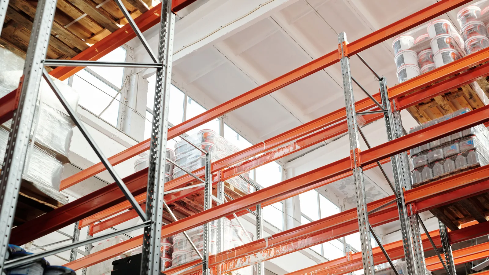 Bright warehouse interior with orange metal shelving units and stored goods.