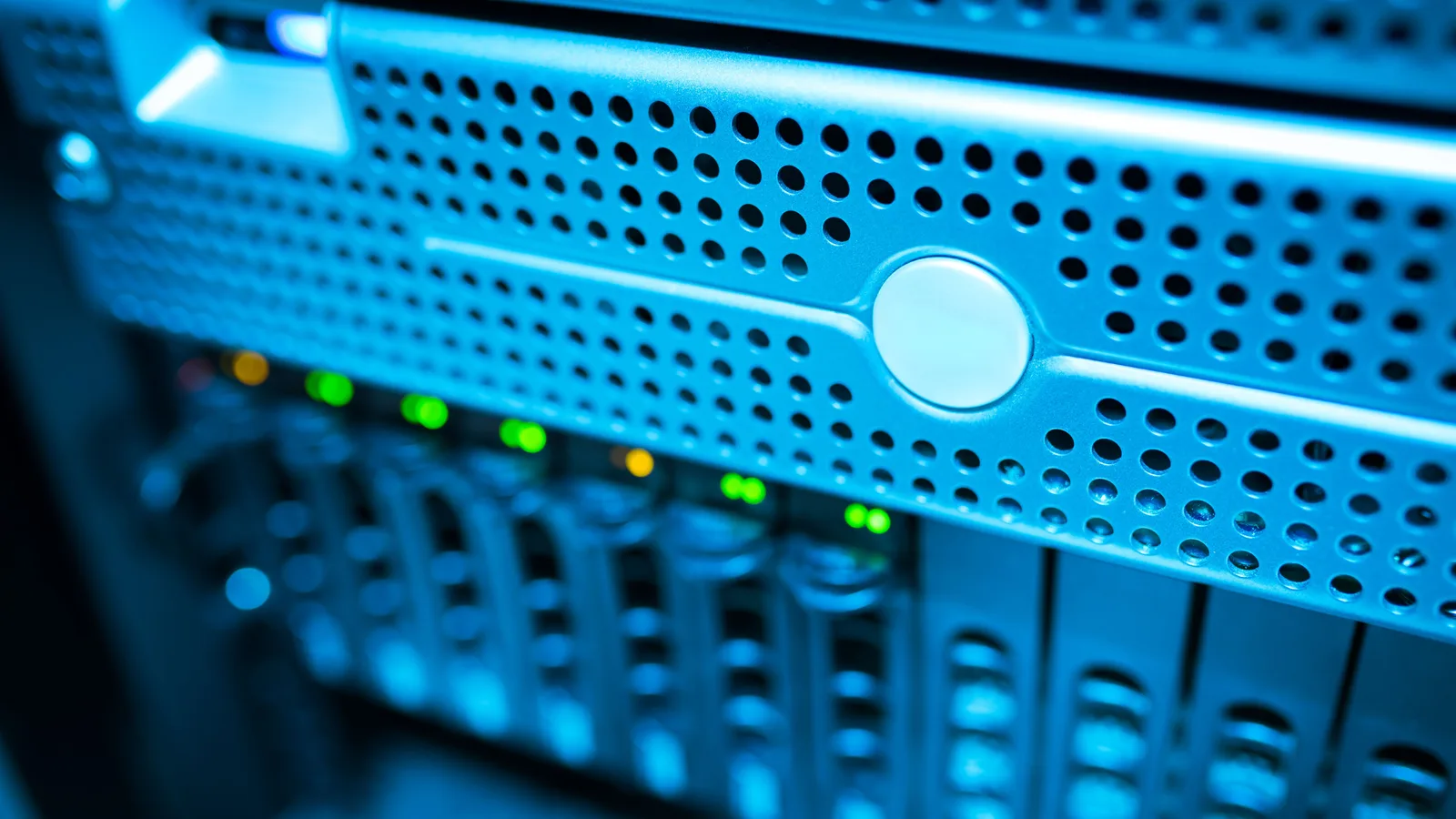 Focused view of a modern data server rack with blinking lights in a blue-lit environment.